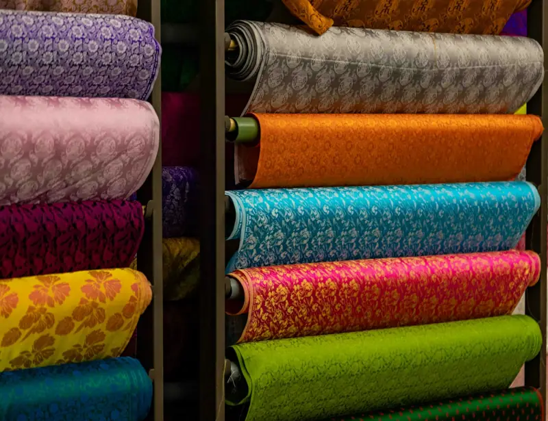 Rolls of dyed and printed woven fabric on shelves
